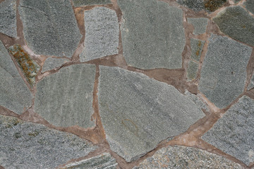 Fragment of a wall of gray stones of an arbitrary shape fastened with concrete