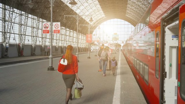 Covered railway station with train and hurrying people