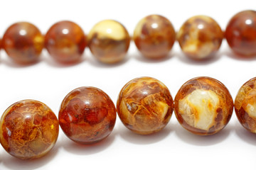 Amber. Beads made from natural yellow brown amber mineral on a white background. Fashionable jewelry amber beads from round and oblong beads. Sun stone as a jeweler raw material. Frozen Resin Fossil