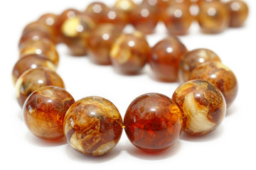 Amber. Beads made from natural yellow brown amber mineral on a white background. Fashionable jewelry amber beads from round and oblong beads. Sun stone as a jeweler raw material. Frozen Resin Fossil