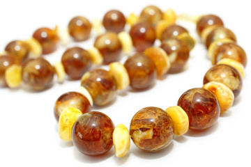Amber. Beads made from natural yellow brown amber mineral on a white background. Fashionable jewelry amber beads from round and oblong beads. Sun stone as a jeweler raw material. Frozen Resin Fossil