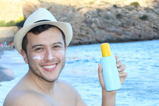 Ethnic man showing sunscreen at the beach 