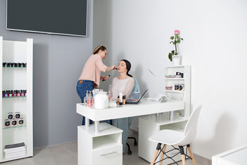 Make up artist applying blusher to brunette girl in beauty salon. Beauty treatment