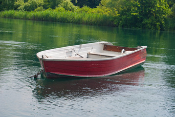 Fototapeta na wymiar Red metal boat for fishing in the Adda river