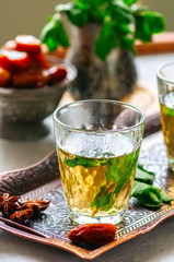 Traditional moroccan mint tea with dates on a vintage tray. White stone background. Close up.