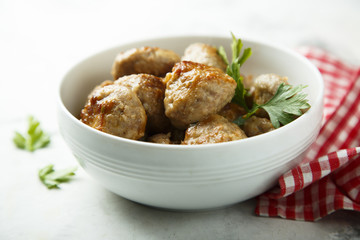 Homemade meatballs with fresh parsley in a white bowl