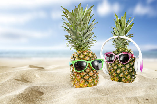 summer photo of pineapple on sand 