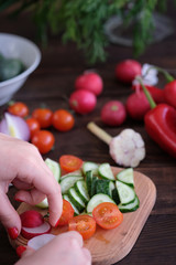 Fresh vegetables sliced for a salad on a cutting board, on an old wooden table