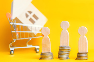 People stand on coins on the background of a wooden house in Supermarket trolley. Concept of real...