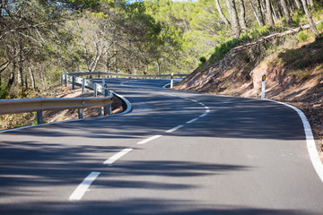 sinuous asphalt road through highlands covered with forests