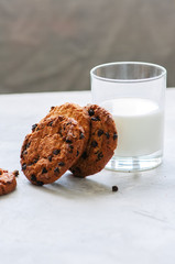 American chocolate chip cookies with glass of milk on a white stone background. Top view and copy space.