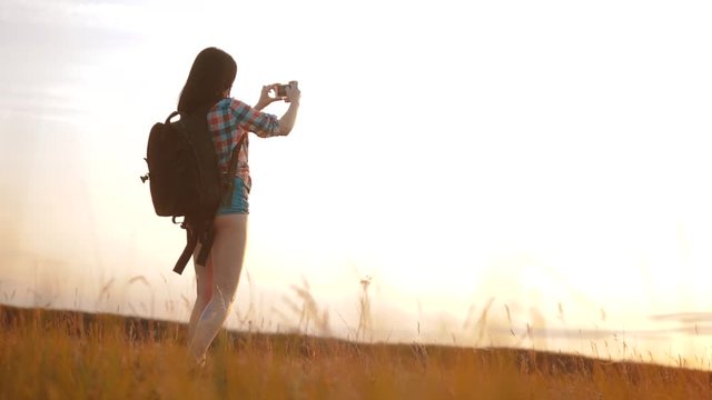 Hipster hiker silhouette girl is shooting video of beautiful nature sundown on cell telephone smartphone slow motion video. Female tourist is taking photo with mobile lifestyle phone camera. female