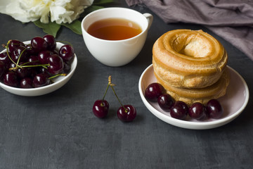 Custard cake rings with cherry on a plate on a dark background. Selective focus. Copy space