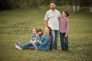 Naklejka na ściany i meble a family of five in the summer in the Park. bearded man and his wife with red hair with three children. happy family.