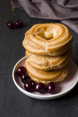 Custard cake rings with cherry on a plate on a dark background. Selective focus. Copy space