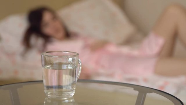 Glass of water and on the background of a man and a woman in bed.