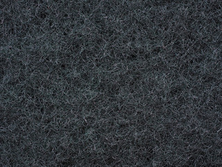 Close-up of dark gray fabric fibrous texture. A plurality of fibers are woven together and form a...