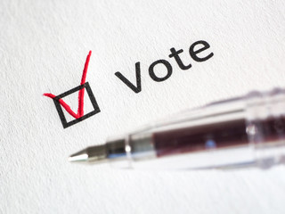 Questionnaire. Red pen and the inscription VOTE with check mark on the white paper. Close-up background. High-quality macro photography.