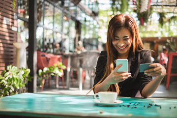 Young beautiful asian woman using smart phone and credit card for shopping online in coffee shop cafe, vintage tone color