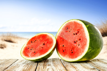Summer photo of watermelon on white wooden table and sea landscape with blue sky. Free space for your decoration. 