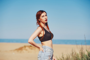 Fototapeta na wymiar Young red-haired woman on the beach
