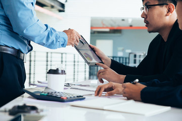 Asian businessmen convened for a meeting with  digital graphs and charts describing their work.