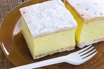 Cream pie with layers of puff pastry in plate on wooden table