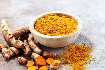 Turmeric powder and fresh turmeric on grey background