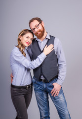 Beautiful young woman and young man are standing in an embrace on a gray background in the studio