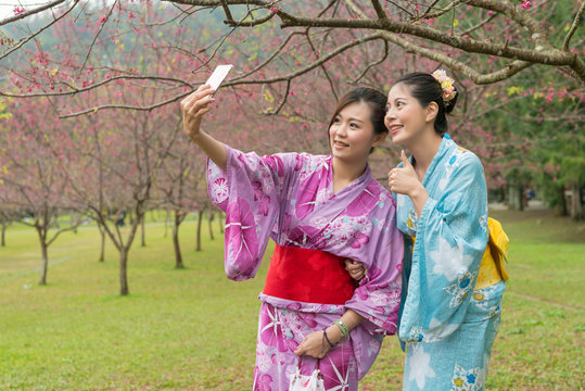 young Asian females taking selfie under the tree