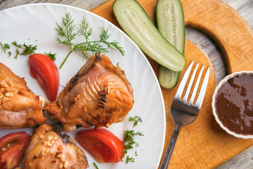 Chicken thighs grilled, tomato, cucumber and sauce on a wooden background