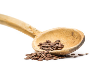 Linseed or flax seed on a tilted wooden spoon from upper left seen from low angle isolated on white background