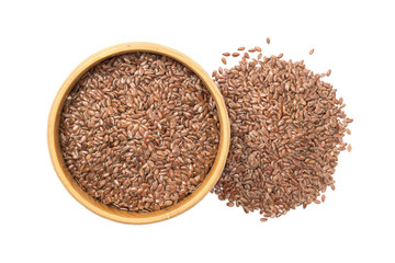 Linseed or flax seed in a wooden bowl and a pile to the right of it seen from above isolated on white background