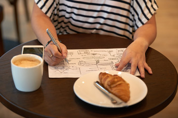 Close-up shot of unrecognizable manager wearing striped T-shirt brainstorming on ambitious project while sitting at coffeehouse table