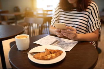 Busy manager sitting at cafe table and texting with colleague on smartphone while working on start-up project, close-up shot