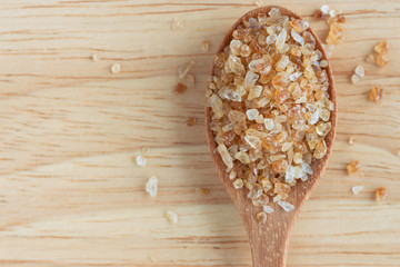 Close up natural brown sugar or no bleach sugar on wooden spoon put on wood table in top view flat lay with copy space. Sweet seasoning for good health. Ingredient prepared for cooking and beverage.