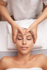 Overview of young woman enjoying facial spa massage in Asian beauty salon