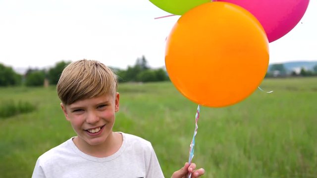 A teenager holds balloons. Summer holidays in nature near the lake. Celebration and fun.Child's birthday