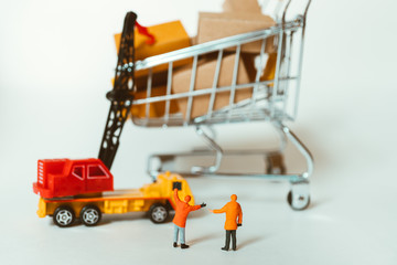 Miniature people, engineer working at construction site with mini shopping cart using as business, industrial and logistics concept