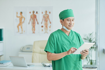 Asian surgeon working on tablet pc at office