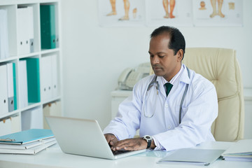 Serious Indian doctor using his laptop for work
