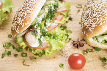 fast junk food delicious hot dog with juicy greenery and bbq sausage on the table close to Cherry tomato