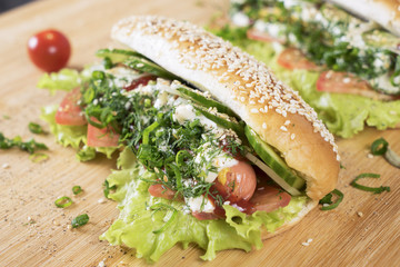 fast junk food delicious hot dog with juicy greenery and bbq sausage on the table close to Cherry tomato