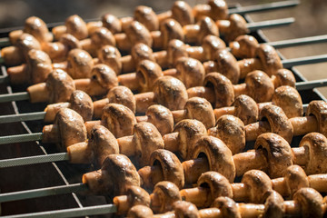 Grilled mushrooms on skewers cooked in a brazier, close-up