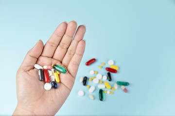 medicine pills,tablets and capsules in the hand on blue background