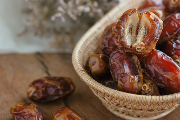 Khalas date palm on wooden basket in side view with copy space on wood table for background. Dates fruit is food for Ramadan or medjool. Delicious dried fruit with sweet taste and have high fiber.