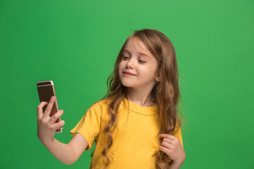Fototapeta premium The happy teen girl standing and smiling against green background.