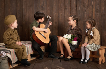 children are dressed in retro military uniforms sitting and playing guitar, sending a soldier to...