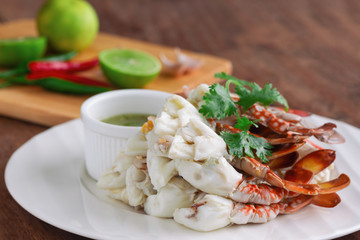 Steamed crab meat prepared for ready to eat with Thai style spicy dipping sauce on white plate put on wood table with copy space for background or wallpaper. Delicious homemade seafood concept.