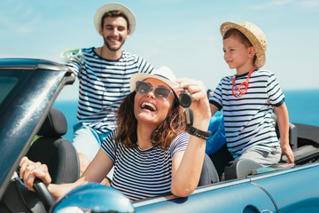 Happy family travel by car to the sea. People having fun in cabriolet. Summer vacation concept